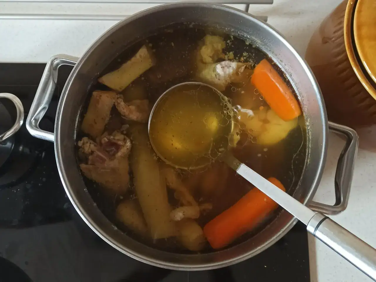 Gotuje się aromatyczny ros&oacute;ł z indyka z marchewką i innymi warzywami. Chochelka nabiera złocisty płyn.