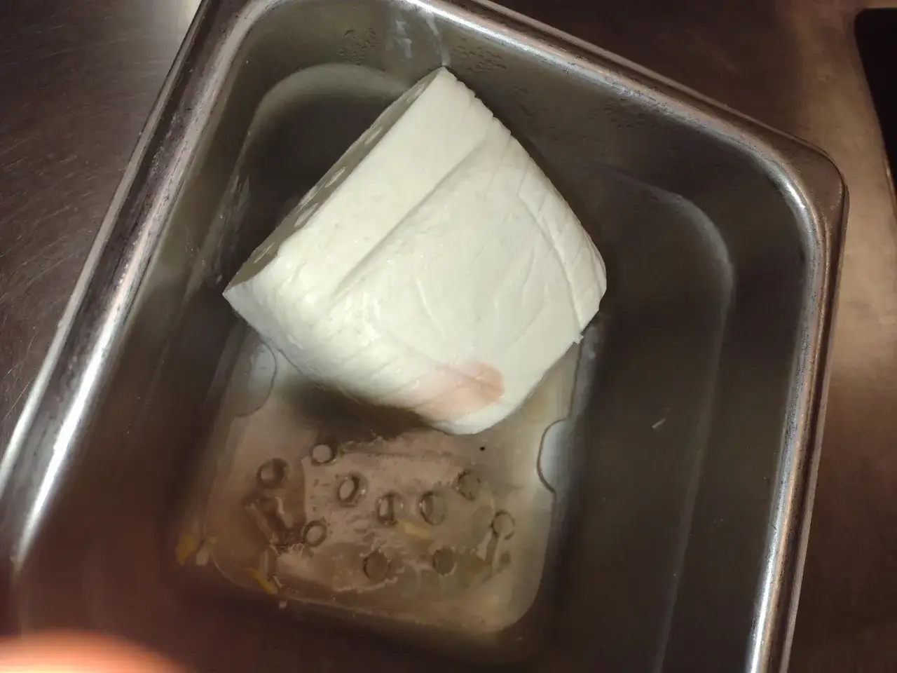 Kawałek mozzarelli w metalowym pojemniku. Czy mozna jesc mozzarelle po terminie? Zależy od jej wyglądu i zapachu.