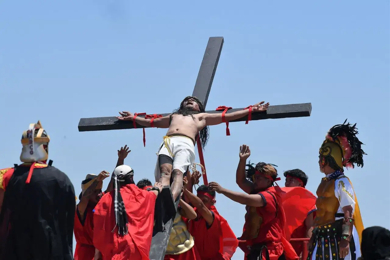Filipiny religia: inscenizacja ukrzyżowania Jezusa podczas Wielkiego Tygodnia. Ludzie w strojach niosą krzyż, odtwarzając scenę biblijną.