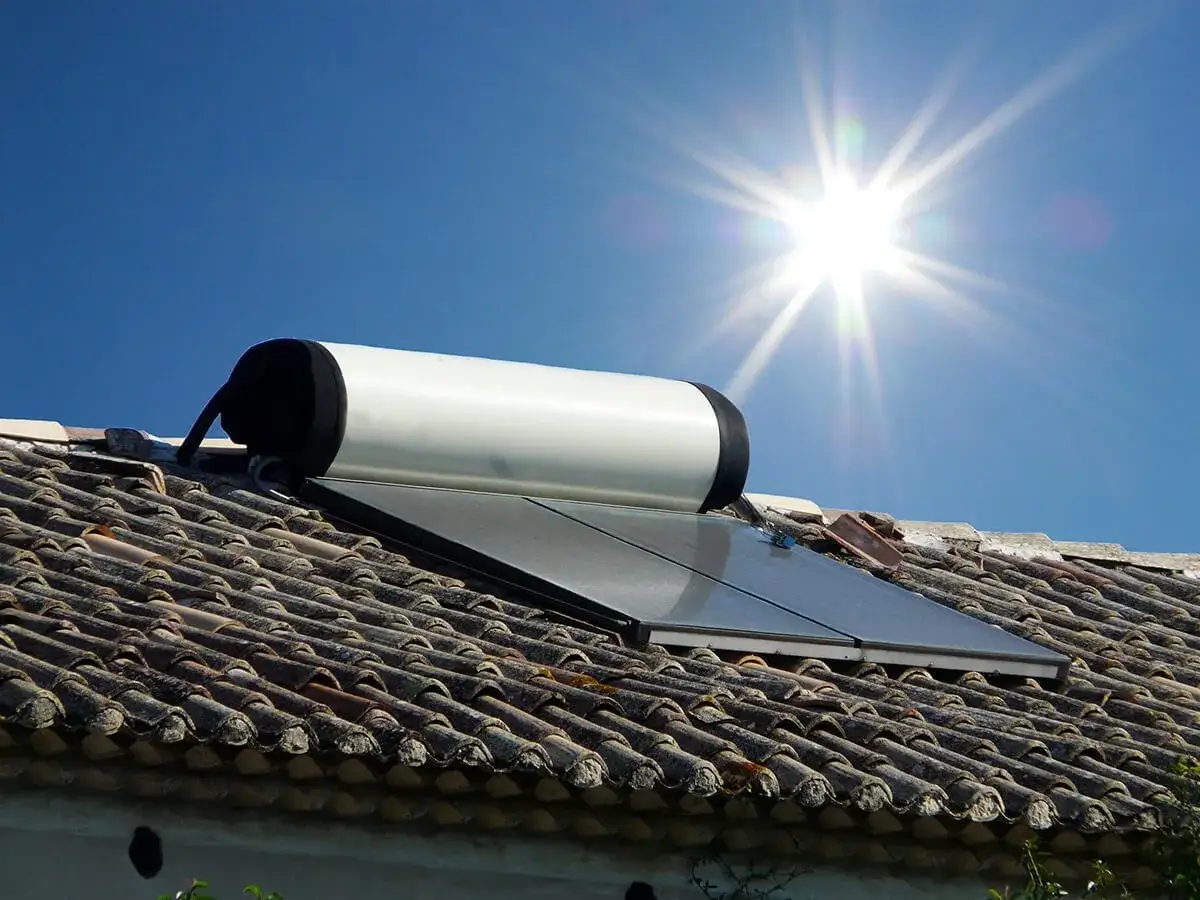 Un chauffe-eau solaire sur un toit de tuiles, sous un soleil éclatant. Un système prometteur pour le rendement chauffe eau solaire.