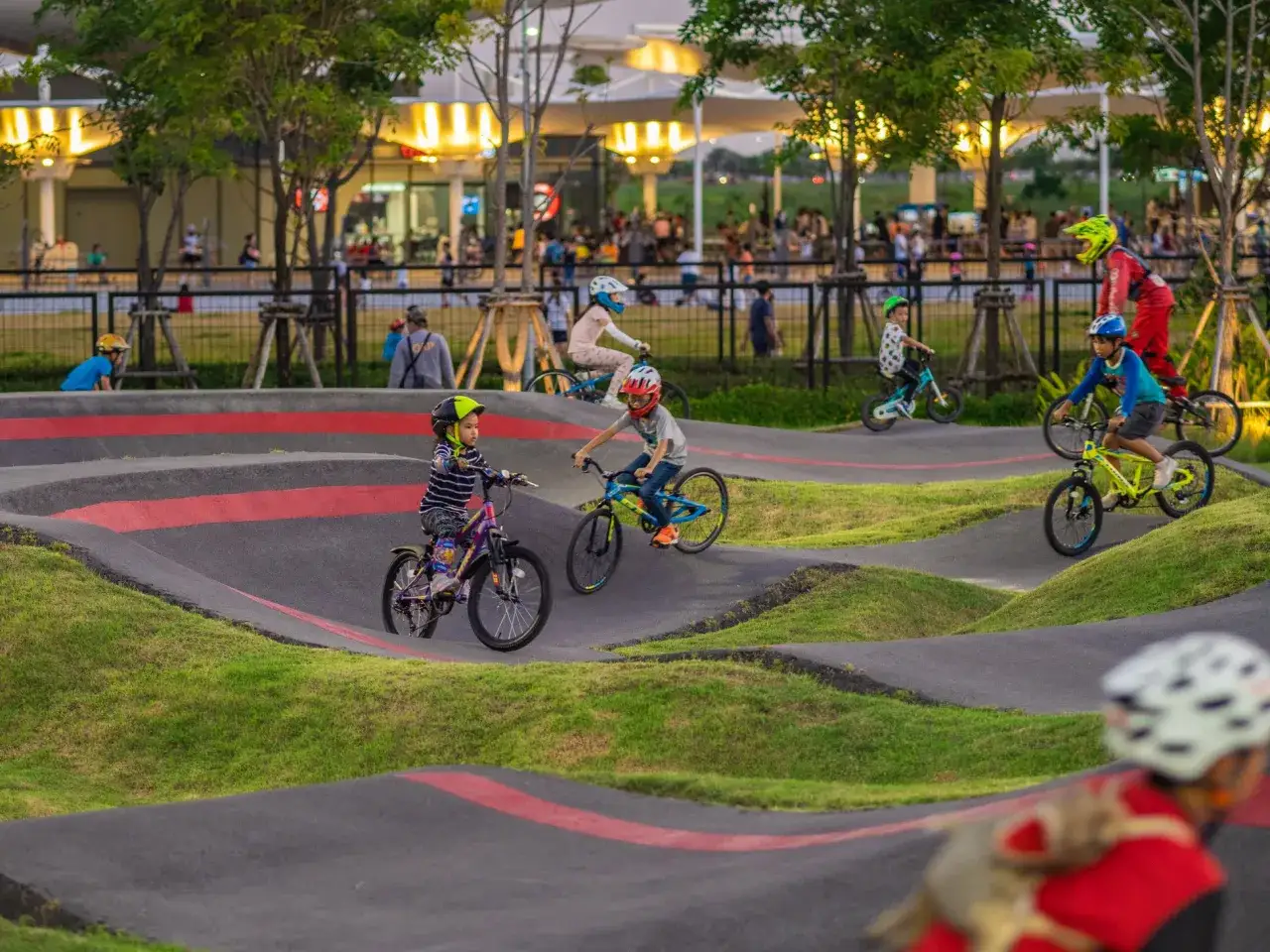 Dzieci na rowerach, w tym rower dla 9 latka, ścigają się po torze pumptrack.