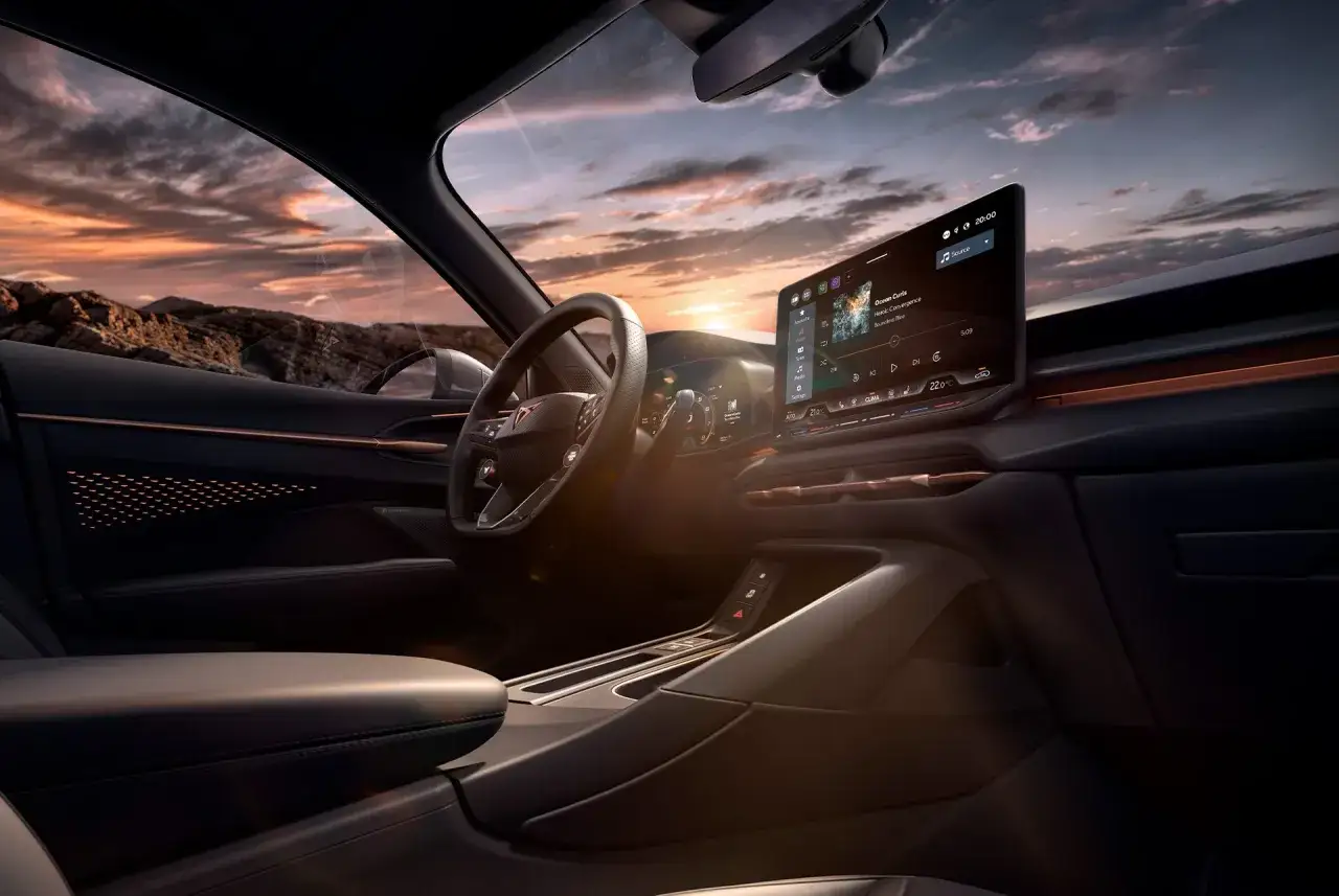 Interni moderni della Cupra Terramar con ampio display centrale e volante sportivo, illuminati da un tramonto suggestivo.