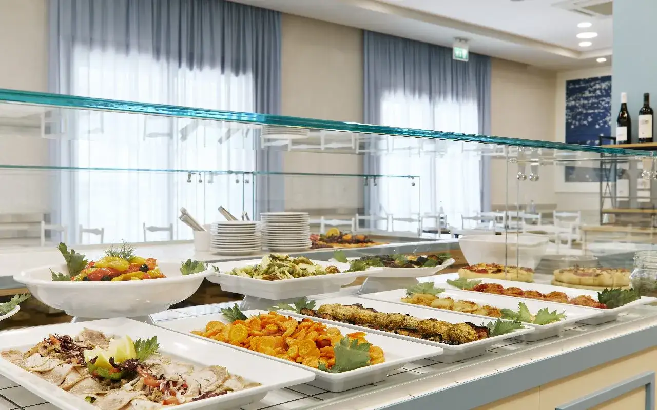 Buffet con pietanze varie: affettati, verdure, pasta, pizze. Un assaggio del **pensione completa significato** in un hotel.
