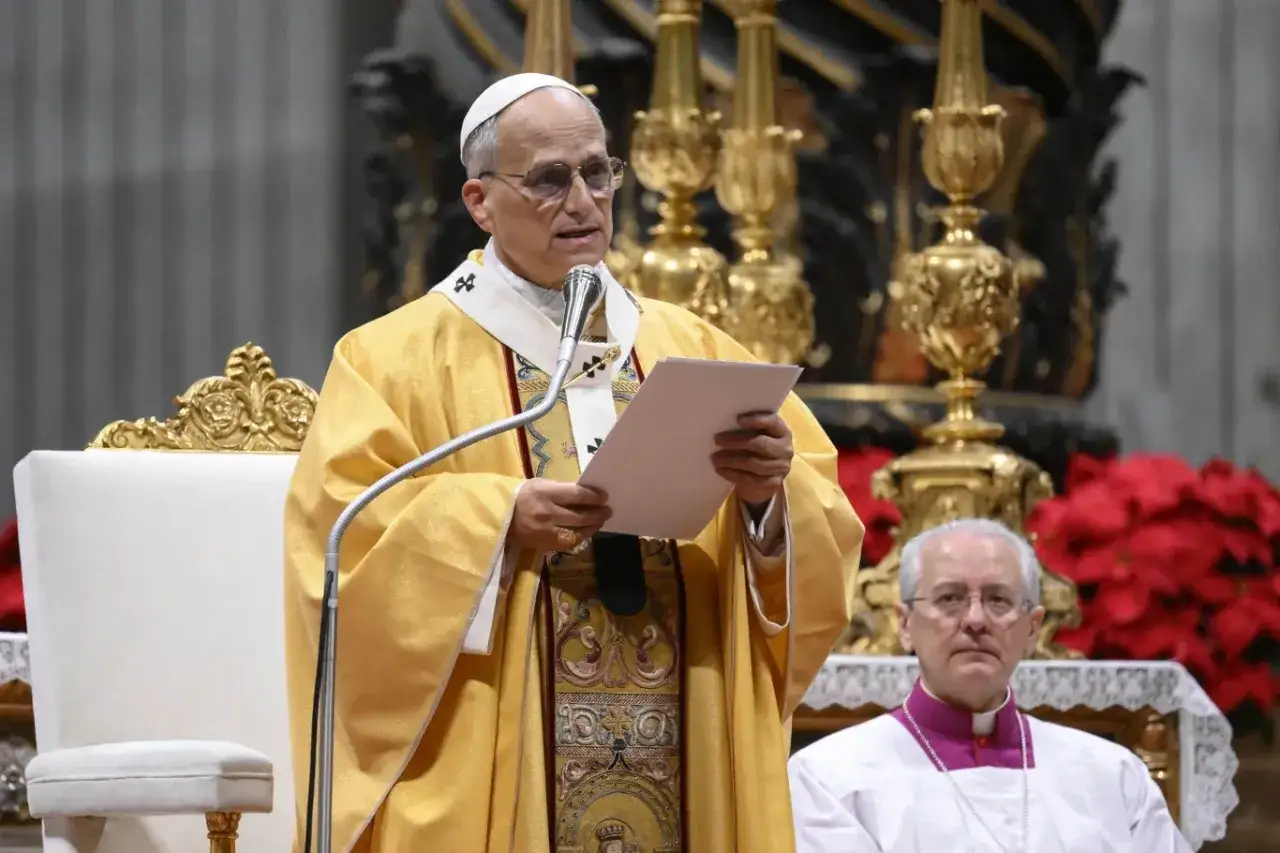 Papież w złotej szacie przemawia podczas zebrania kardynałów. Obok siedzi inny duchowny.
