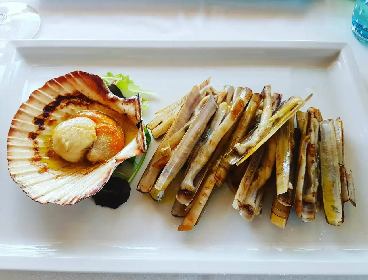 Pyszne frutti di mare: przegrzebek w muszli i grillowane małże nawiązujące do morskich smaków.