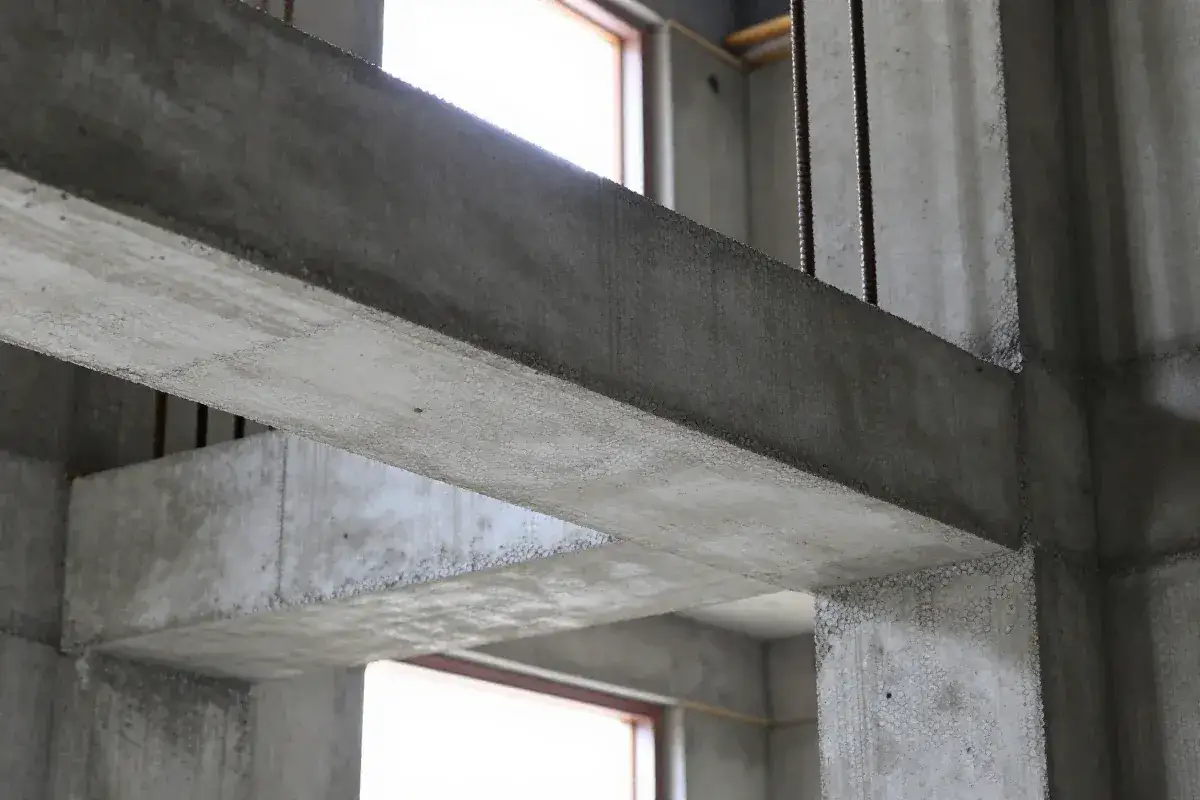 Surowe, betonowe nadproża monolityczne tworzą konstrukcję budynku. Widać stalowe pręty zbrojeniowe.