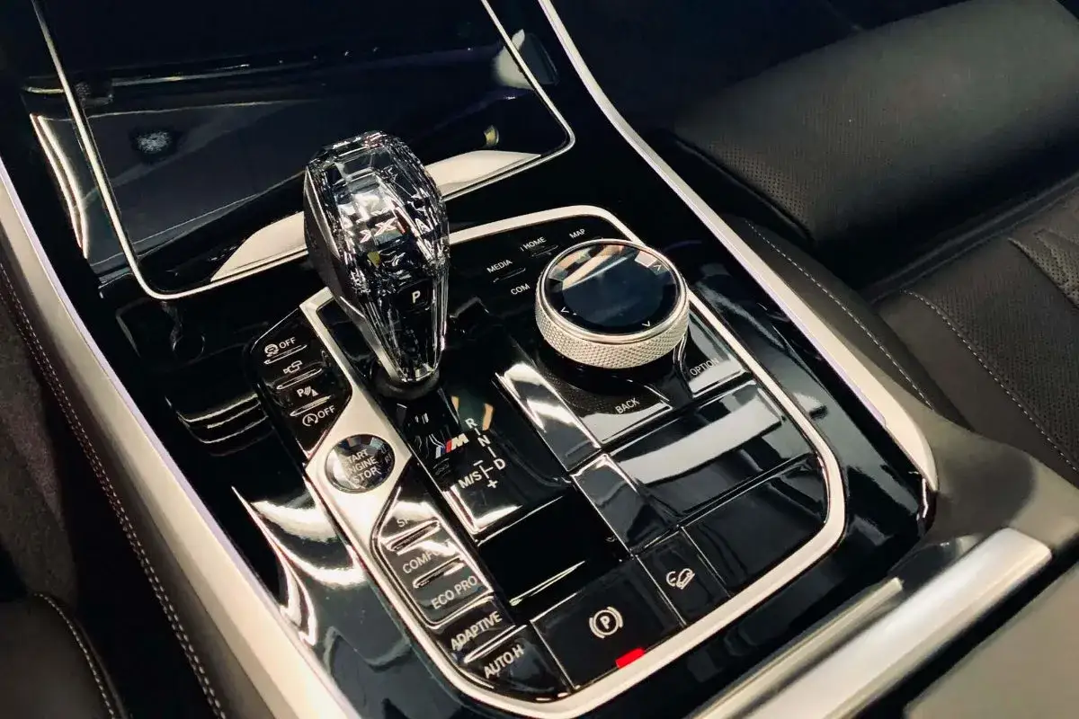Luksusowy panel środkowy z kryształową dźwignią zmiany bieg&oacute;w i pokrętłem iDrive. Detailing wnętrza podkreśla elegancję.