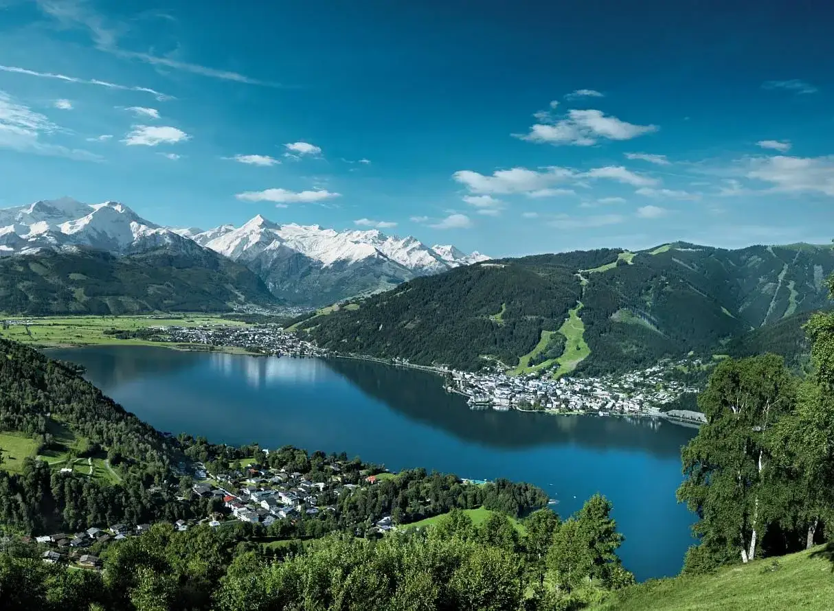 Malownicze jezioro w Austrii, otoczone zielonymi wzgórzami i ośnieżonymi szczytami. Idealne miejsce na camping Austria.