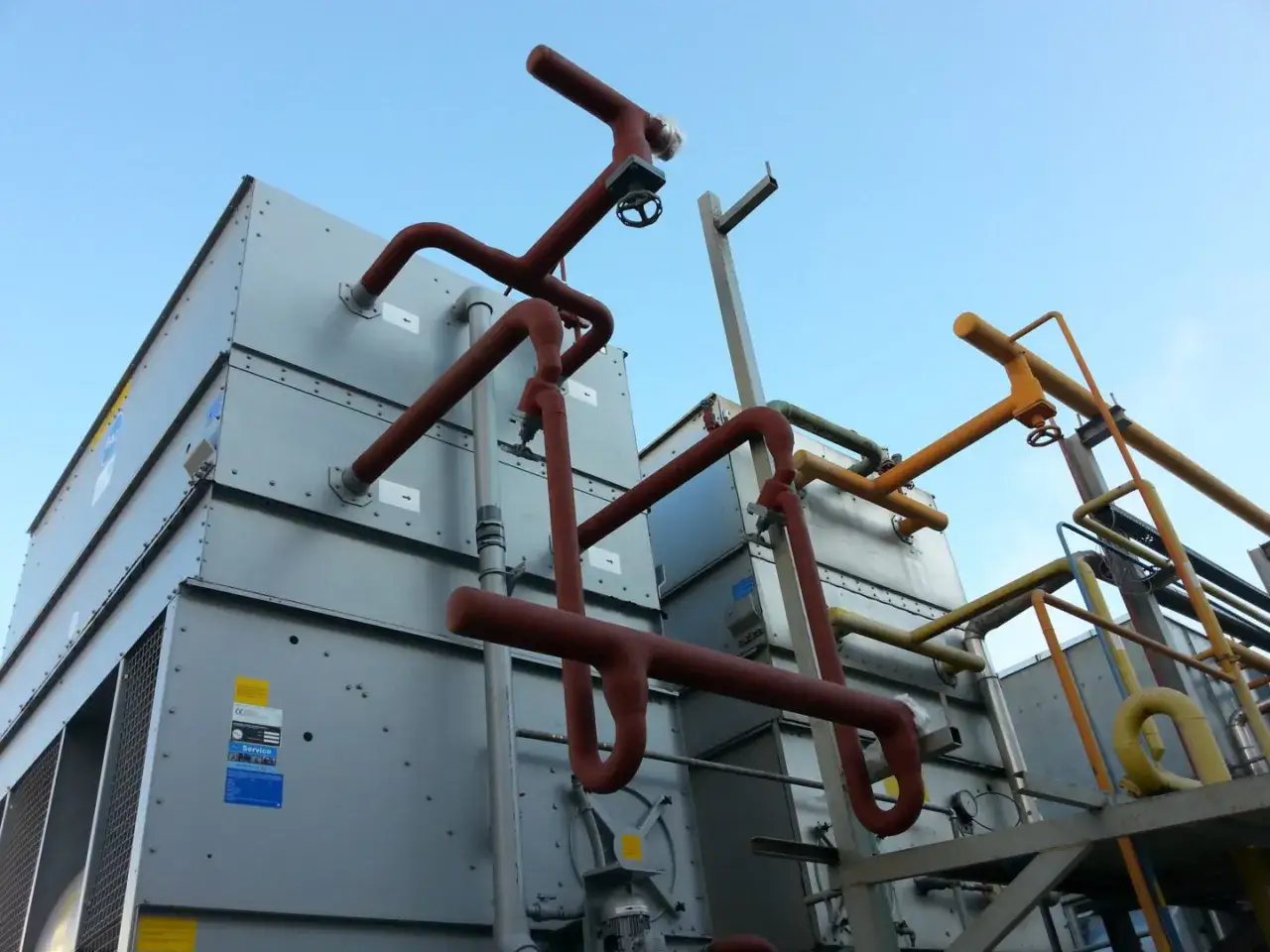 System chłodzenia z rurami, zaworami i dużymi modułami. Widoczne instalacje amoniakalne.