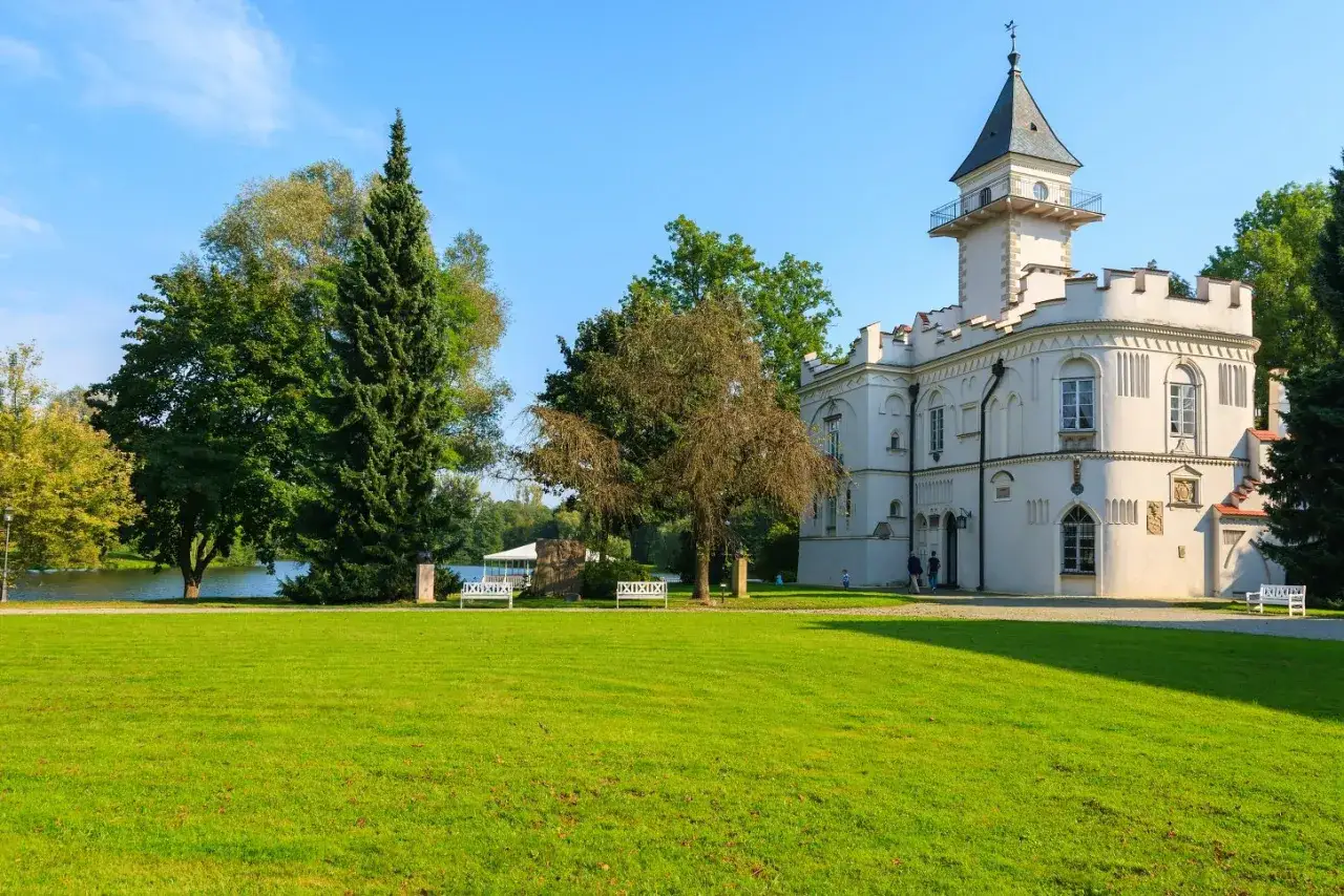 Biały pałac z wieżą, otoczony zielenią i jeziorem, to jeden z najpiękniejszych zamk&oacute;w na Mazowszu.