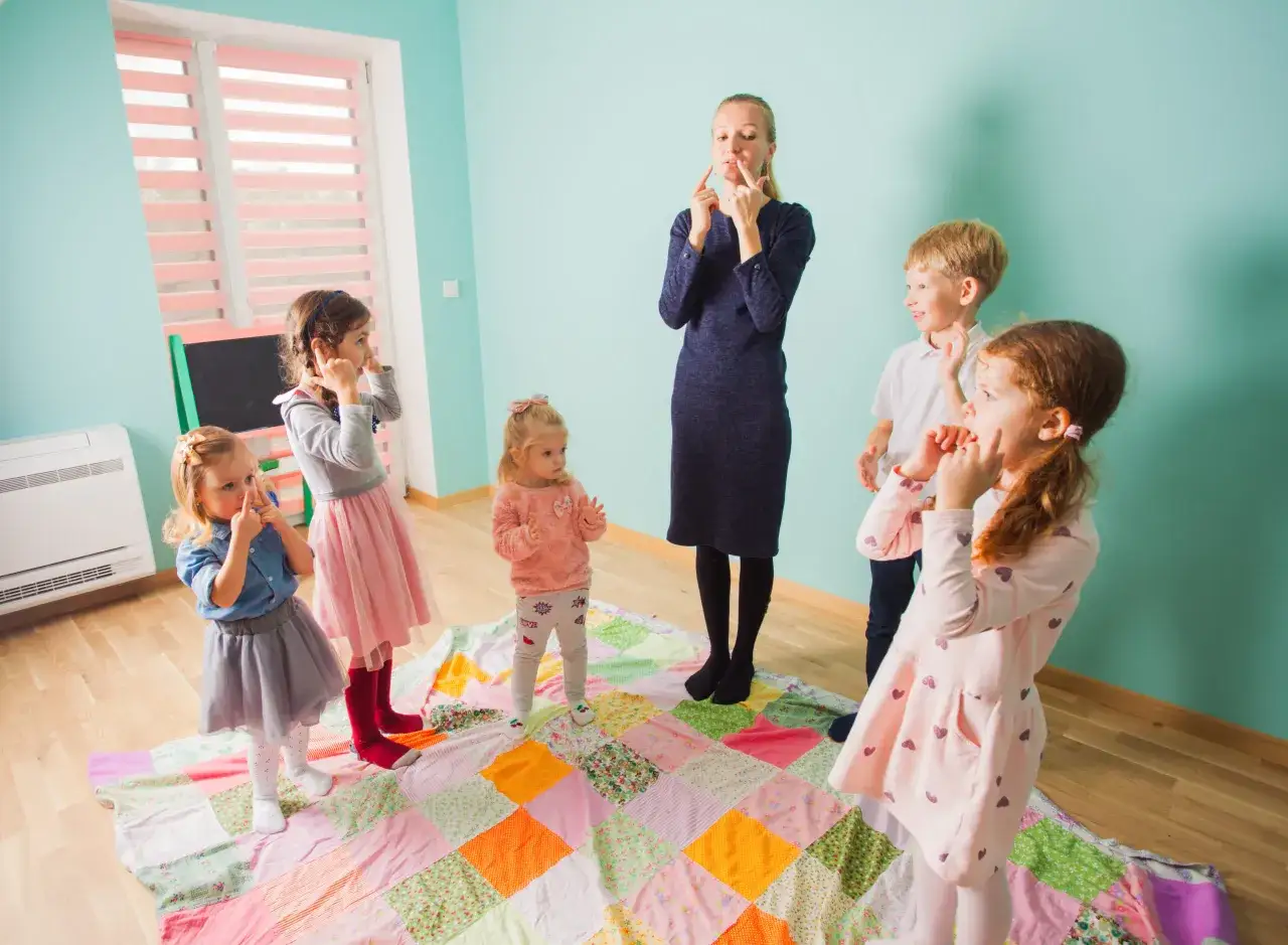 Maestra ense&ntilde;a pronunciaci&oacute;n en ingl&eacute;s en infantil. Ni&ntilde;os imitan gestos de la boca.