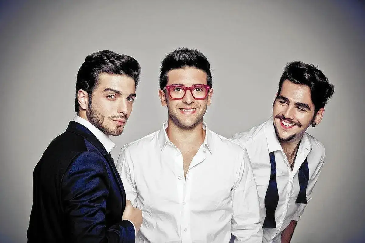 Tre giovani cantanti abruzzesi famosi, sorridenti e vestiti elegantemente, posano per uno scatto promozionale.