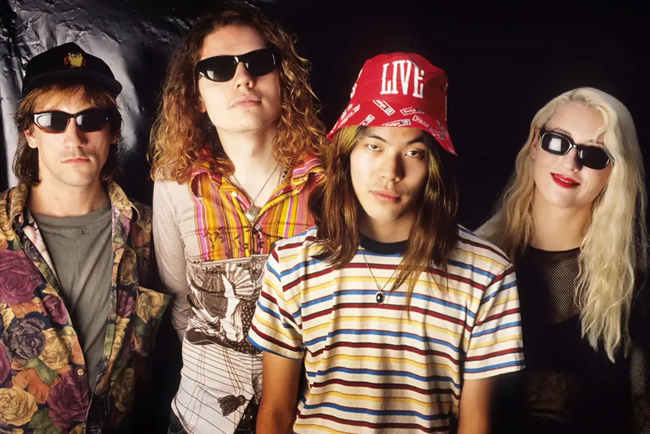 D'Arcy Wretzky 2023, membre du groupe Smashing Pumpkins, pose avec ses acolytes, arborant un style d&eacute;contract&eacute; et color&eacute;.