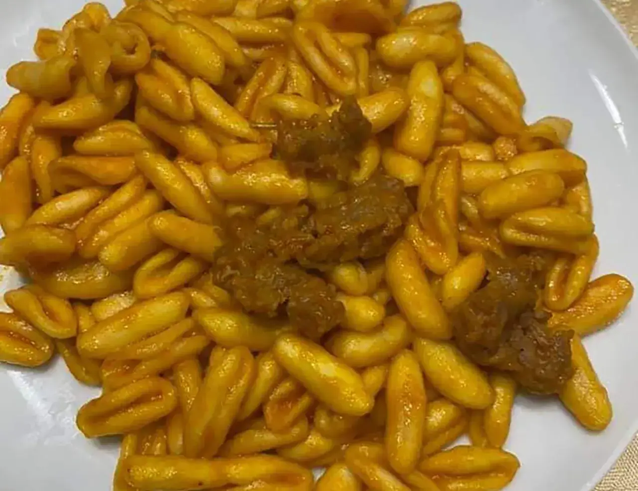 Un piatto di gnocchetti alla campidanese, pasta fresca condita con un sugo ricco e pezzi di carne saporita.