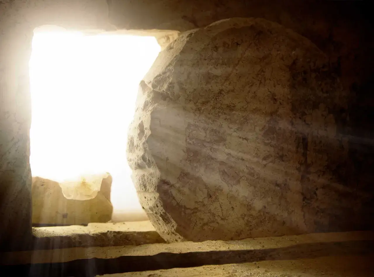 Ein leerer Grabstein mit Lichtstrahlen, die durch die Öffnung fallen. Die Szene symbolisiert die Wiederauferstehung Jesu.
