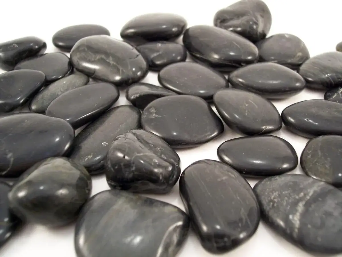 Un mont&oacute;n de piedras negras pulidas, como una piedra negra protectora, brillan sobre un fondo blanco.