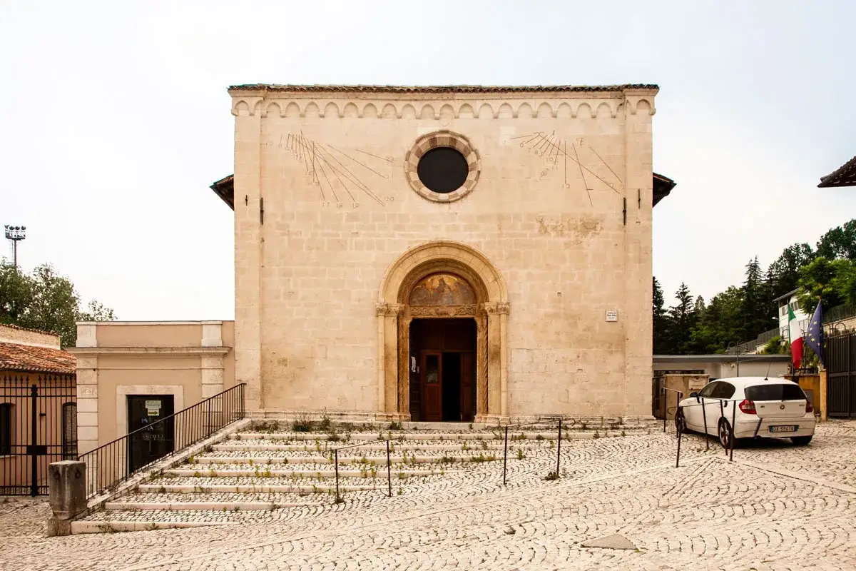 Chiesa romanica con meridiane, un'idea per cosa vedere a L'Aquila in un giorno. Un'auto bianca parcheggiata.