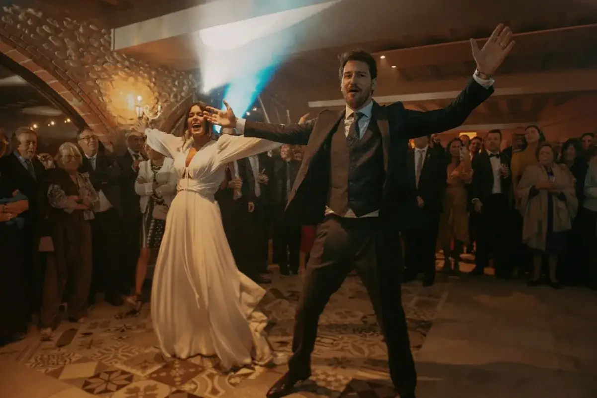 Novios bailando su vals boda con alegr&iacute;a, rodeados de invitados.