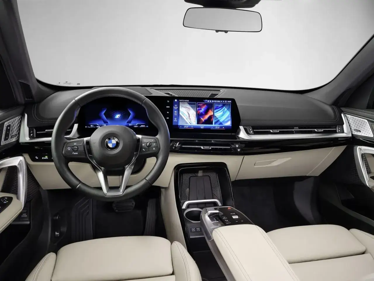 Wnętrze BMW iX1 z nowoczesnym kokpitem, cyfrowymi ekranami i skórzaną tapicerką.