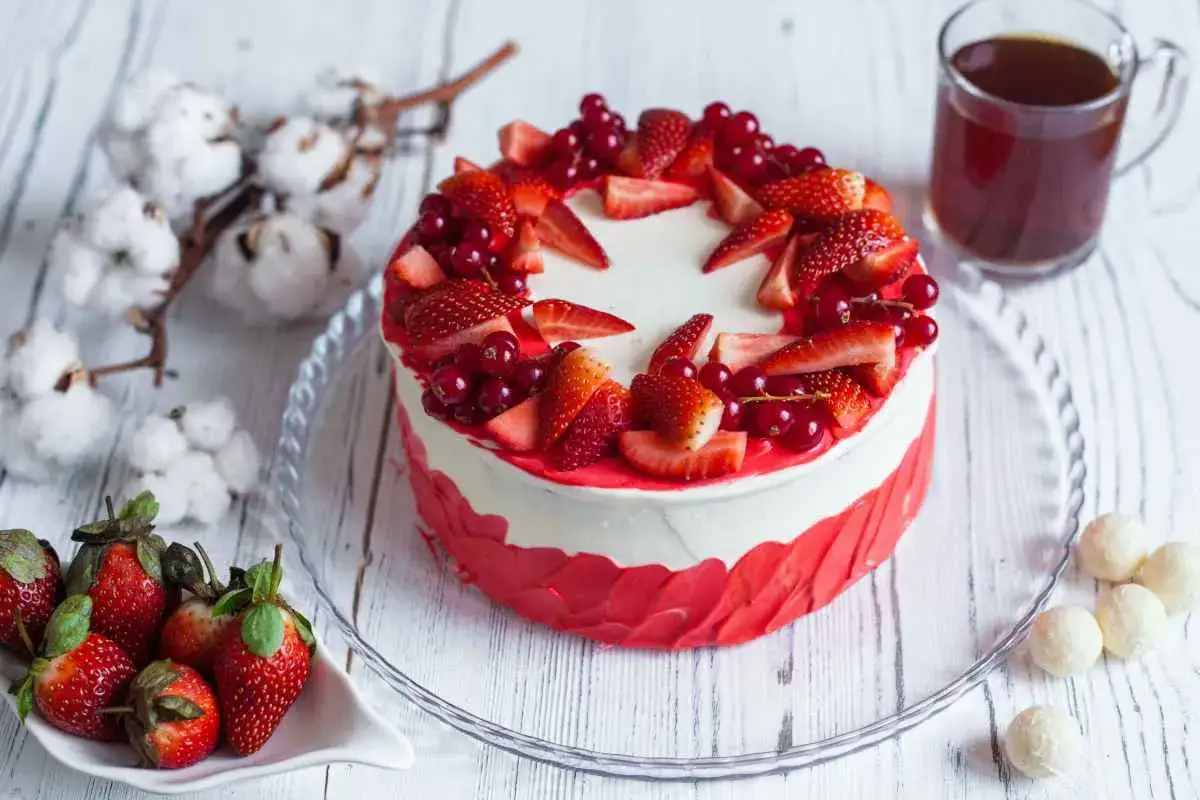 Torte di buon compleanno decorate con fragole fresche e ribes. Accanto, chicchi di caffè e cotone.