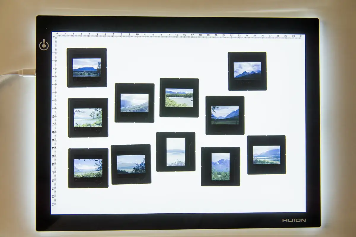 Samling av analoga bilder med vackra landskap, placerade p&aring; en ljusplatta.