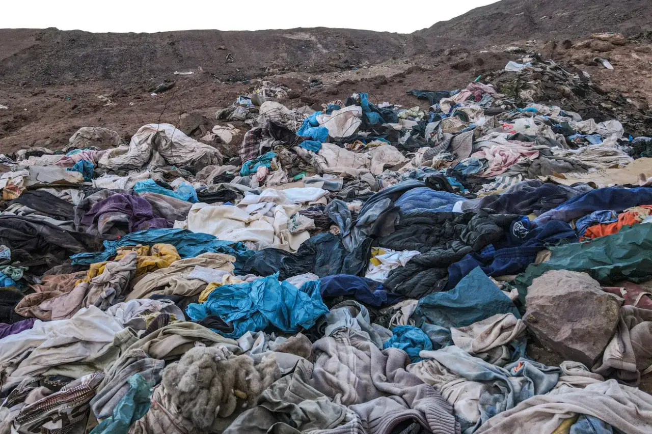 Góra wyrzuconych ubrań, świadectwo skutków kupowania ubrań fast-fashion dla środowiska i portfela.