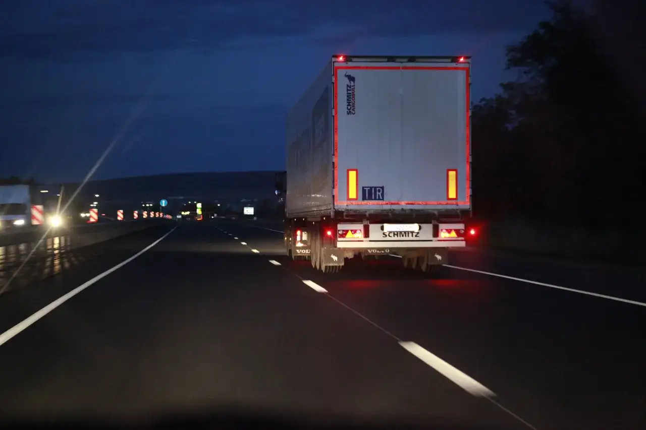 Ciężarówka na autostradzie w godzinach nocnych. Kierowcy TIR-ów pokonują długie dystanse, często w trudnych warunkach.