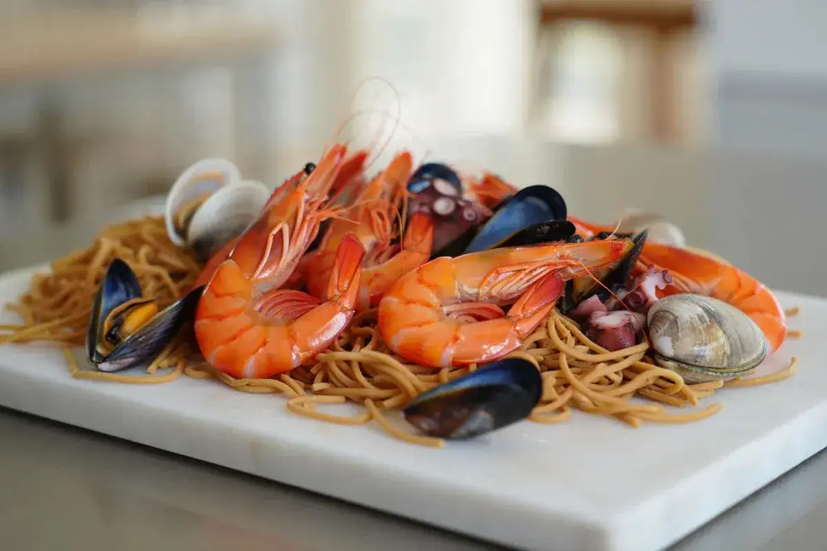 Deliciosa fideuà mixta con gambas, mejillones, almejas y pulpo sobre fideos dorados.