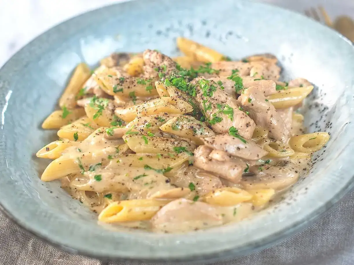 Krämig kyckling svamp pasta med penne, toppad med persilja och svartpeppar. En härlig middag!