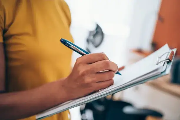 Osoba wypełniająca formularz papierowy z długopisem
