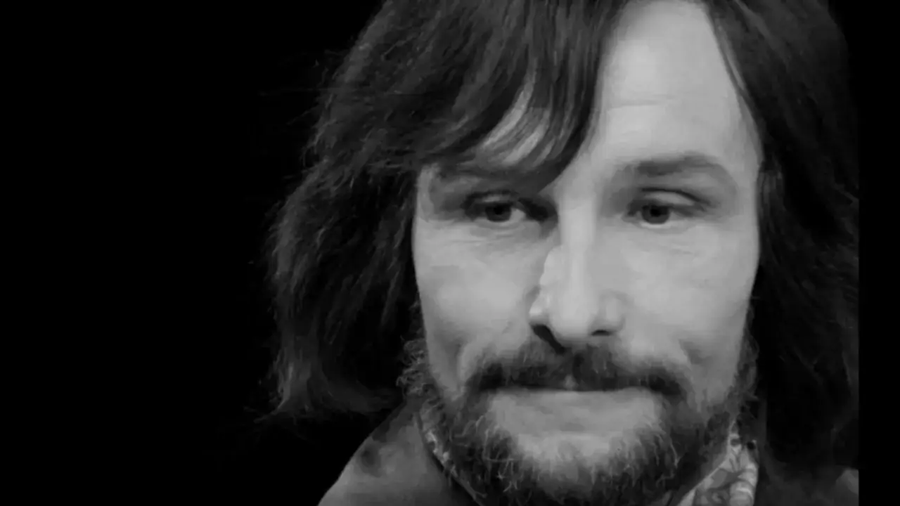 Zbliżenie na twarz Henryka Bistę, aktora znanego z wielu filmów. Jego charakterystyczna fryzura i zarost są widoczne.