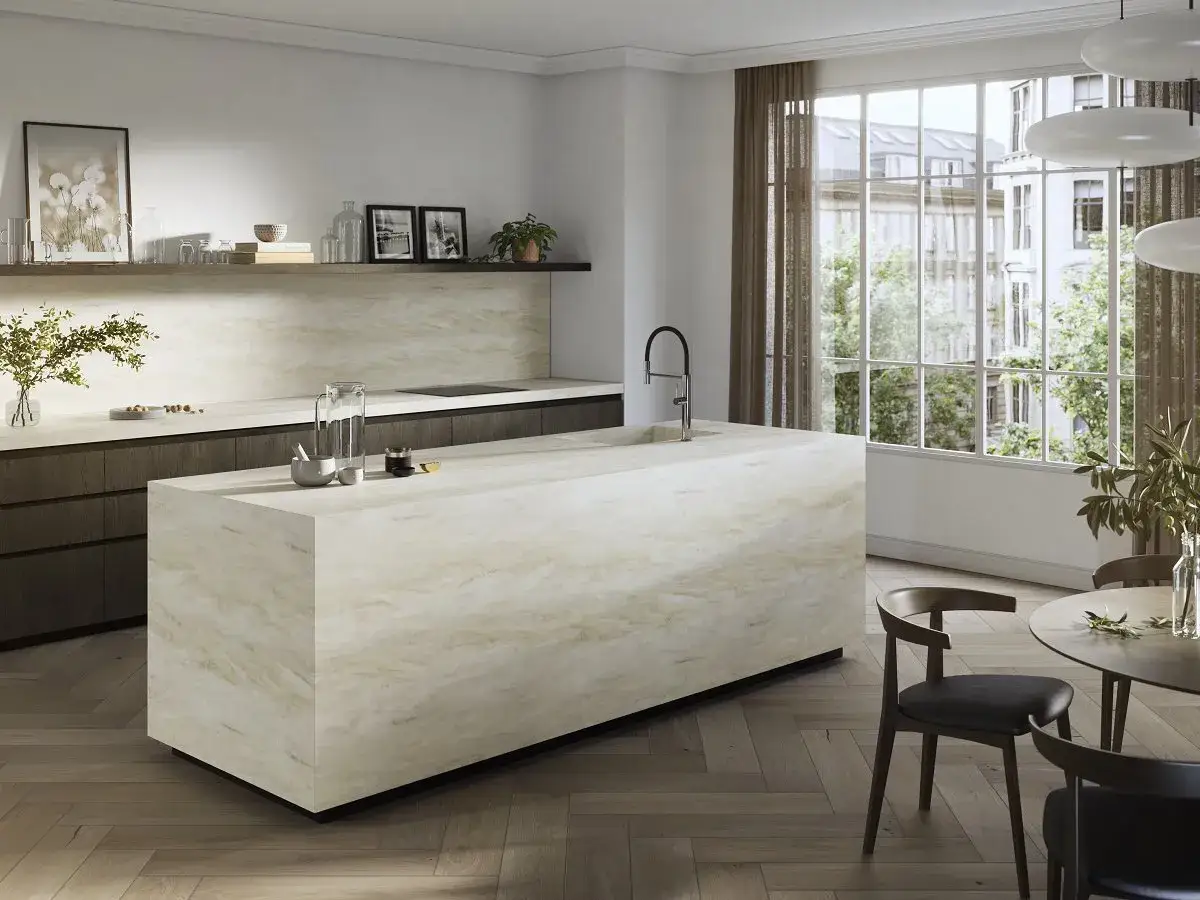Cocina moderna con isla central de m&aacute;rmol, perfecta para reformar una cocina. Tonos c&aacute;lidos y luz natural.