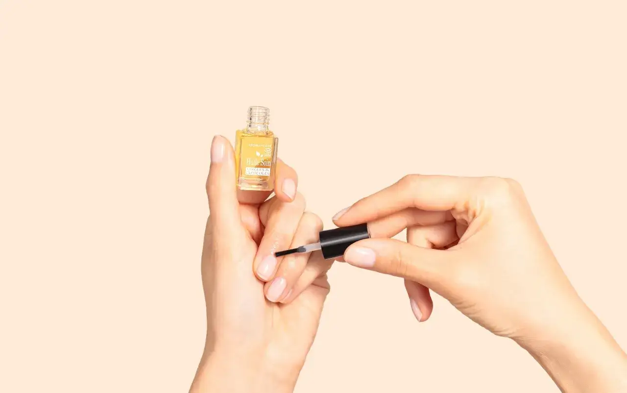 Une astuce grand-m&egrave;re pour des cuticules ongles parfaits : application d'une huile soin.