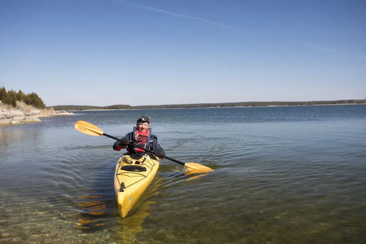 Man paddlar kanot på Gotland i klart vatten med en gul kajak.