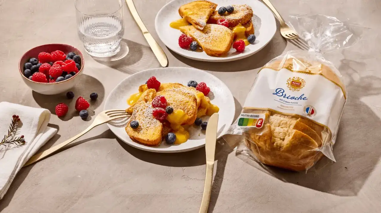 Zwei Teller mit French Toast, garniert mit Beeren und Sauce. Daneben eine Schale mit Beeren und eine Packung Brioche.