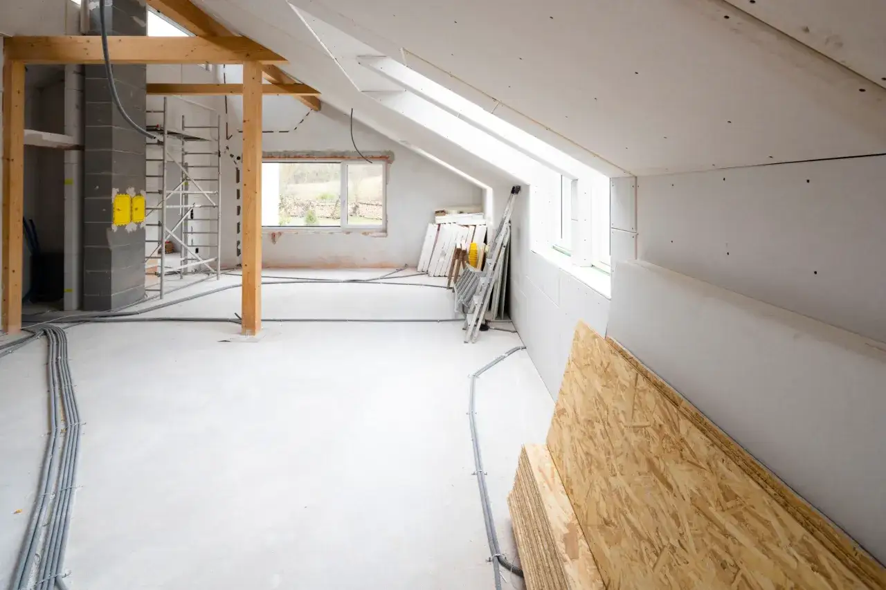 Umbau eines Spitzbodens: Gerüst, Kabel, Gipskartonplatten und Holzwerkstoffplatten warten auf den Einbau.