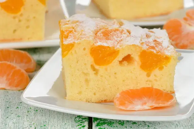 torta di mandarini interi soffice su piatto con spicchi di mandarino