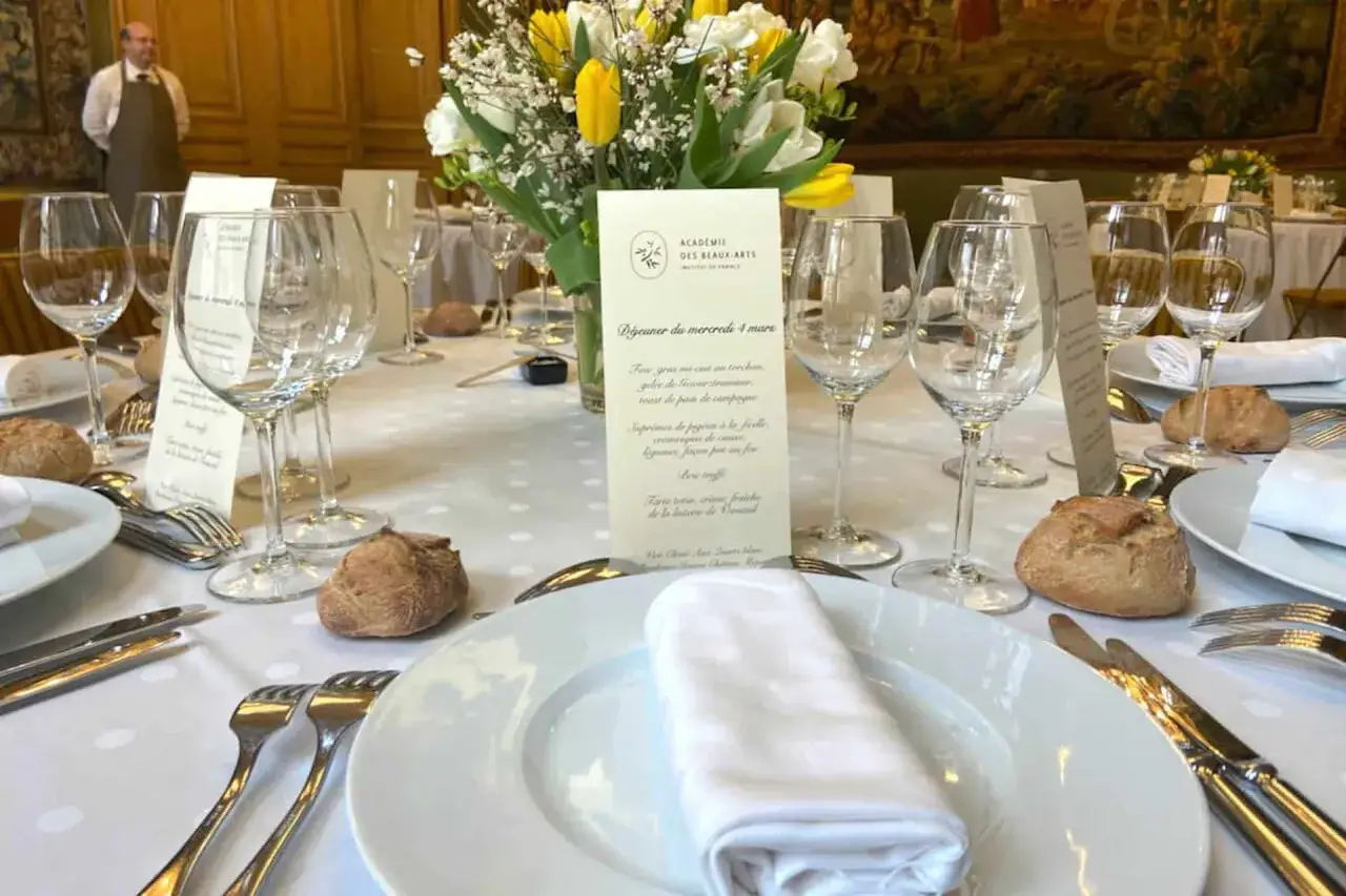 Un dîner élégant avec des verres à pied, des menus et des fleurs, illustrant parfaitement les arts de la table.