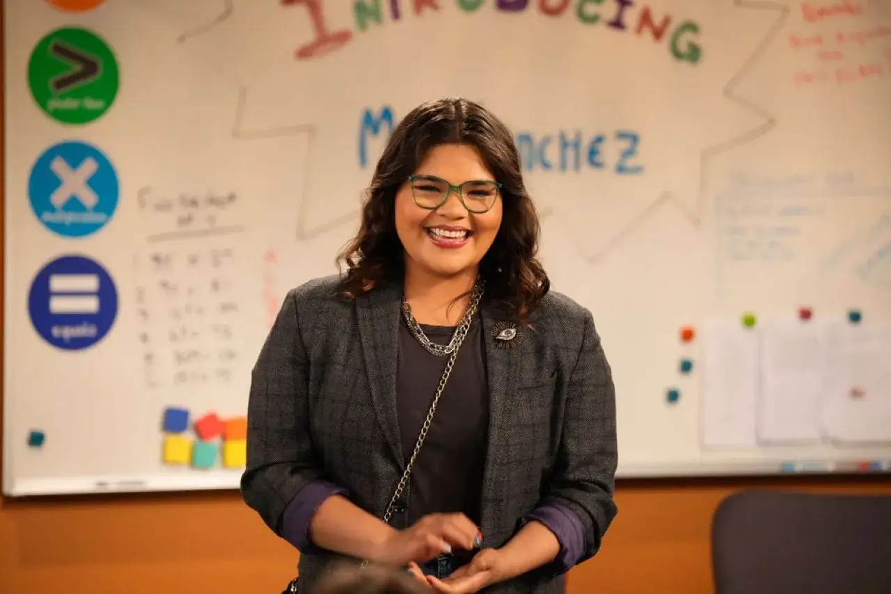 Belissa Escobedo, souriante, devant un tableau avec des symboles mathématiques et des notes. Elle est connue pour ses rôles dans des films et séries TV.