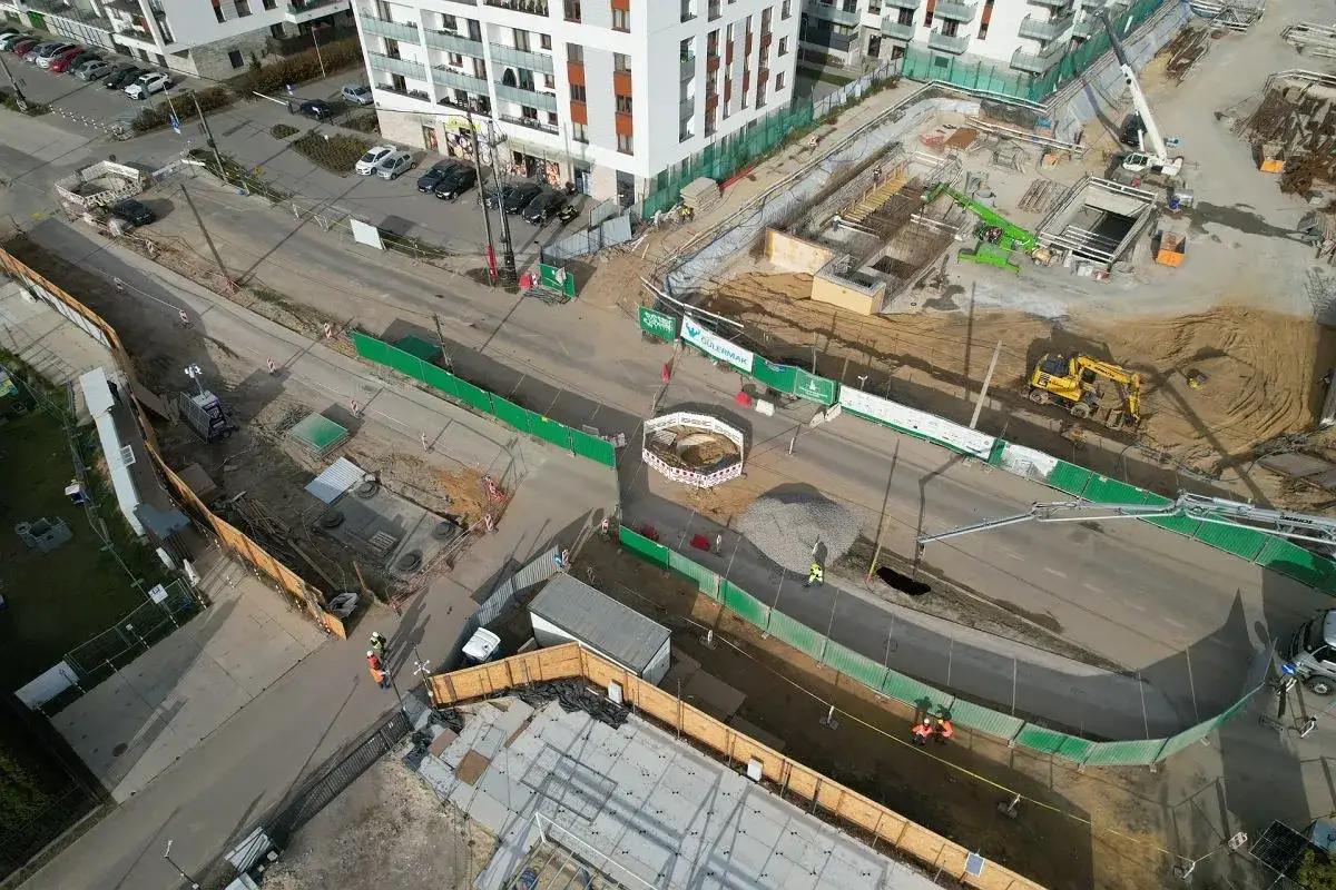 Budowa w Chrzanowie, Warszawa. Plac budowy z koparkami, dźwigami i pracownikami. Nowe bloki mieszkalne w tle.