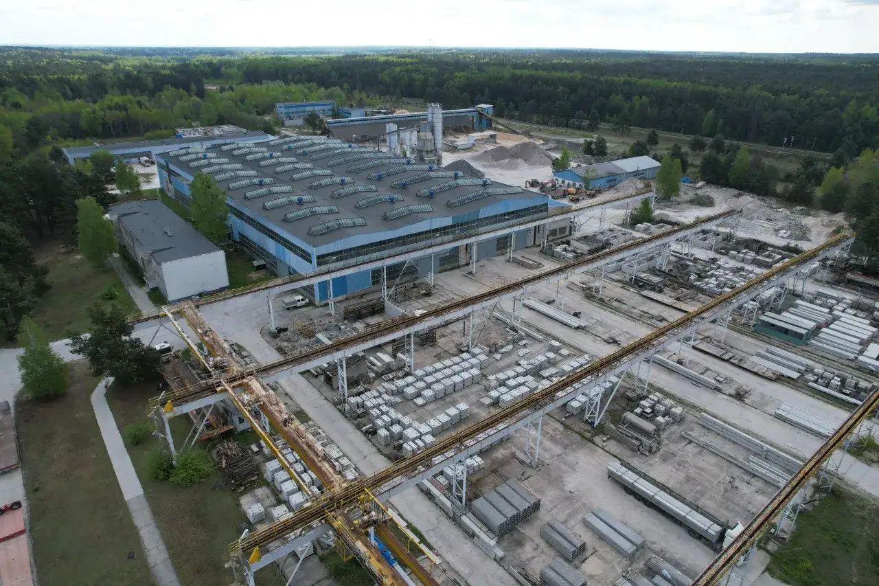 Fabryka domów Bogucin: rozległy teren przemysłowy z halami produkcyjnymi, placami składowymi pełnymi prefabrykatów betonowych i liniami produkcyjnymi.