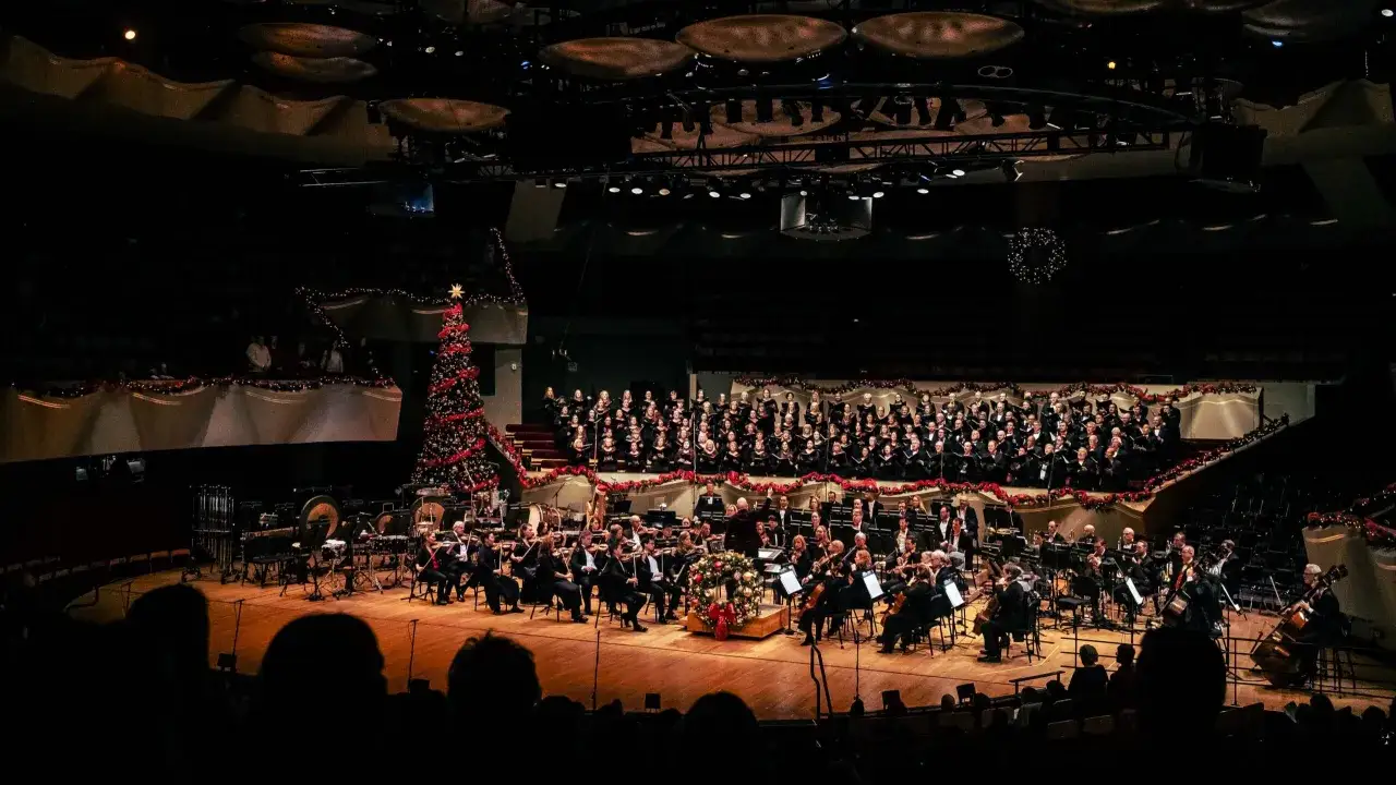 Ein Orchester und Chor bereiten sich auf ein Konzert vor, mit einem Weihnachtsbaum und Dekorationen. Ein Moment der Vorfreude auf best classical music.