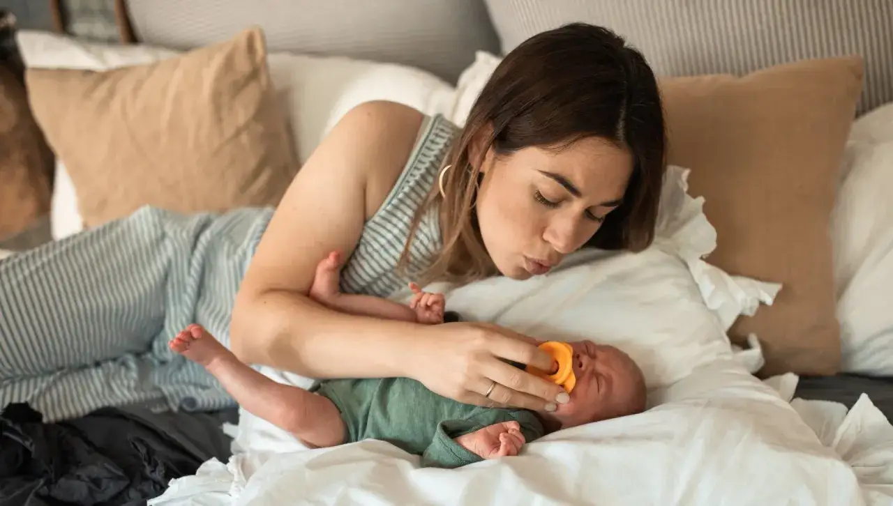 Mamma f&ouml;rs&ouml;ker lugna sin bebis med hicka med en napp.