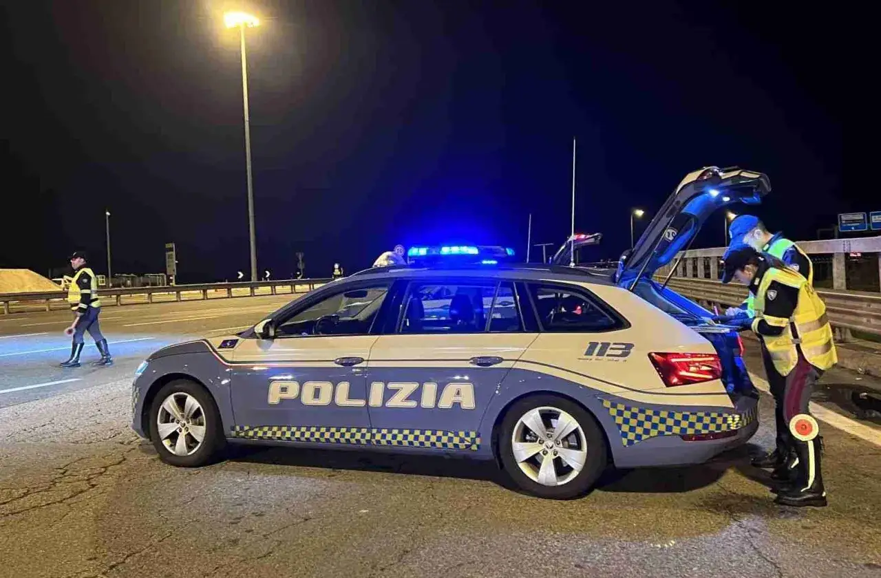 Agenti della Polizia di Stato effettuano un controllo stradale notturno, forse legato all'articolo 12 del codice della strada, con lampeggianti blu accesi.