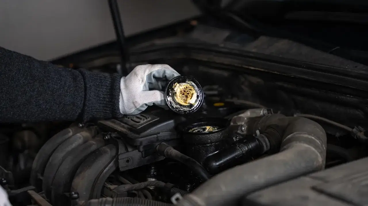 Rękawiczka zdejmuje zakrętkę z silnika Audi 8P, ukazując osad.
