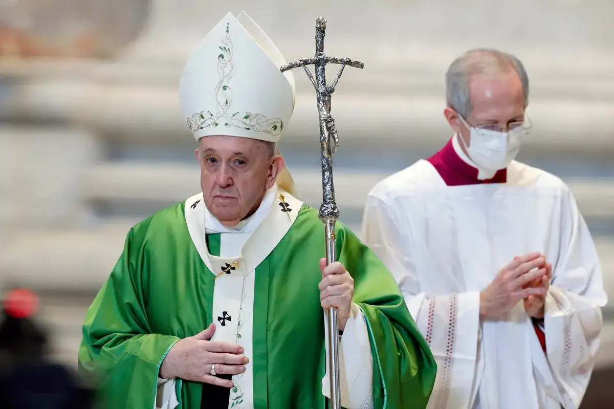 Papież Franciszek, w zielonej szacie i białej mitrze, trzyma pastorał. Jego wzrost jest typowy dla mężczyzny w podeszłym wieku.