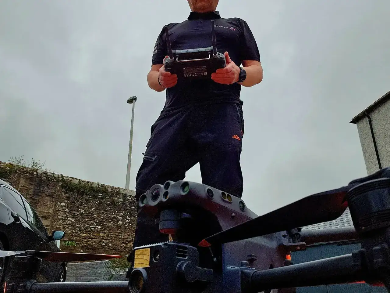 A person in a black polo shirt and pants holds a drone controller, ready to deploy a UAV jammer.