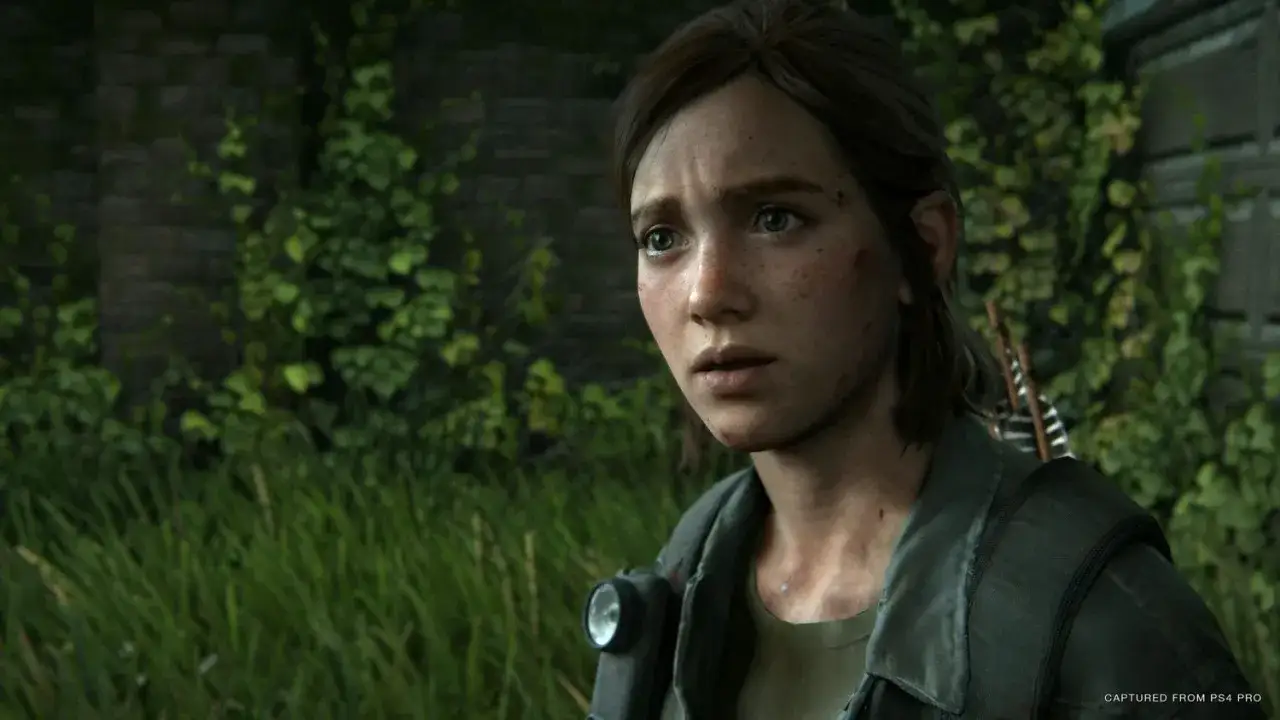 Ellie z The Last of Us 2, zamyślona, w otoczeniu zieleni. Gra oferuje wiele godzin emocjonującej rozgrywki.