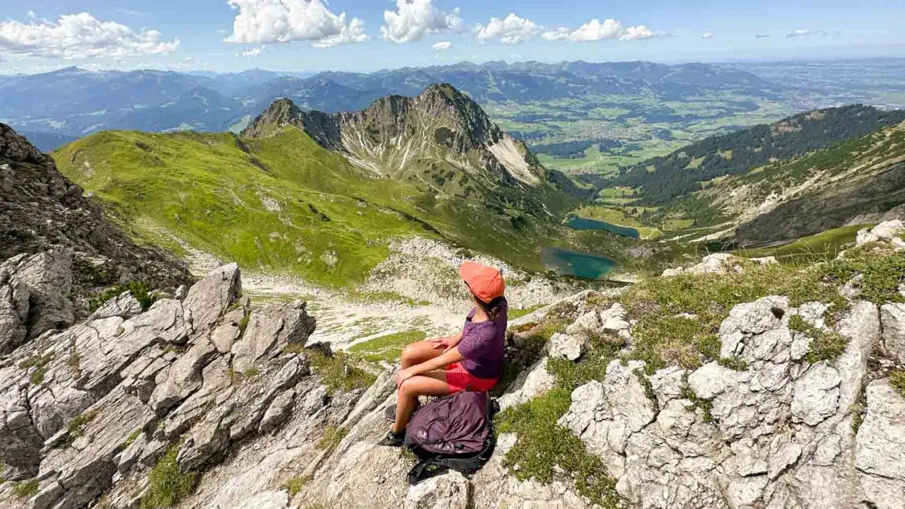 M&auml;dchen sitzt auf Felsen und blickt auf das Kleinwalsertal mit seinen Seen.