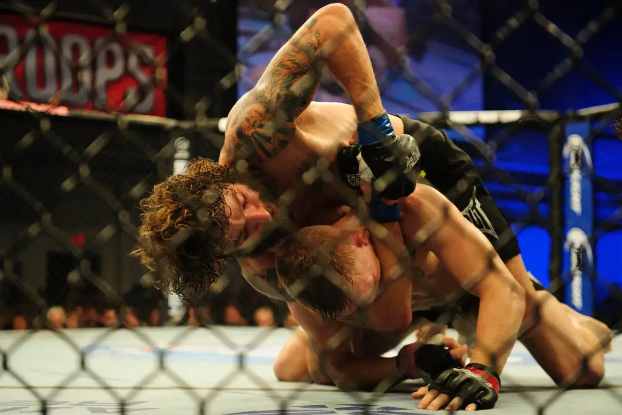 Michael Chiesa i en intensiv brottningsmatch i buren, fokuserad på att säkra en submission.